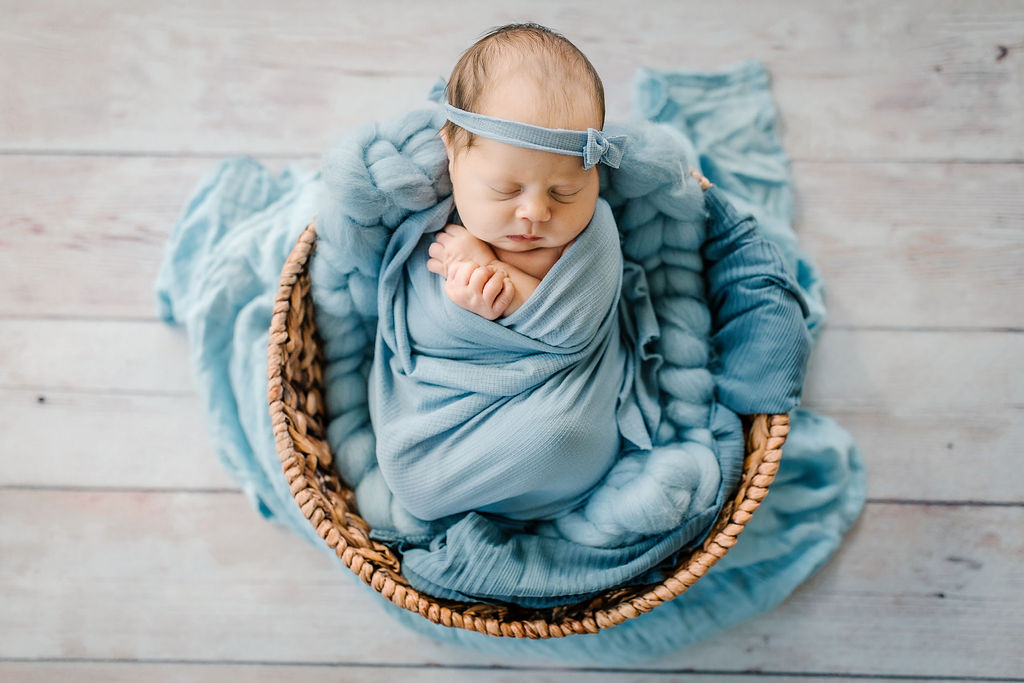 newborn baby sleeps in a woven basket in a studio charlottesville fertility clinic