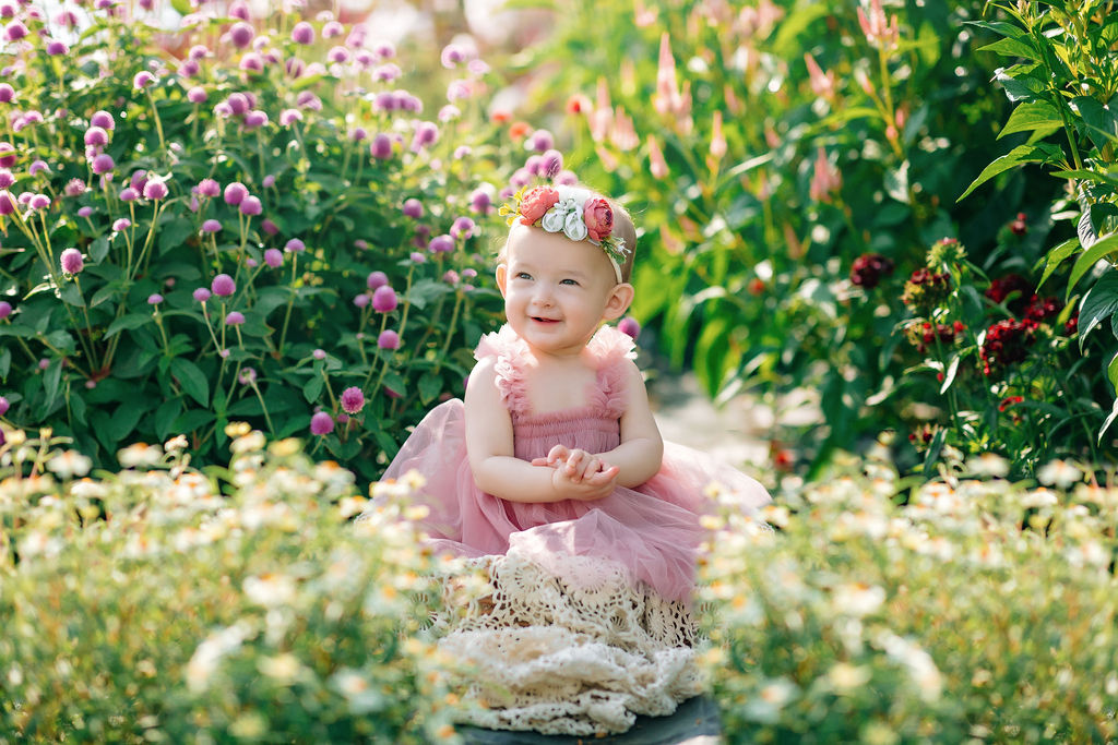 toddler sits in a pink dress among a flower garden pufferbellies staunton va