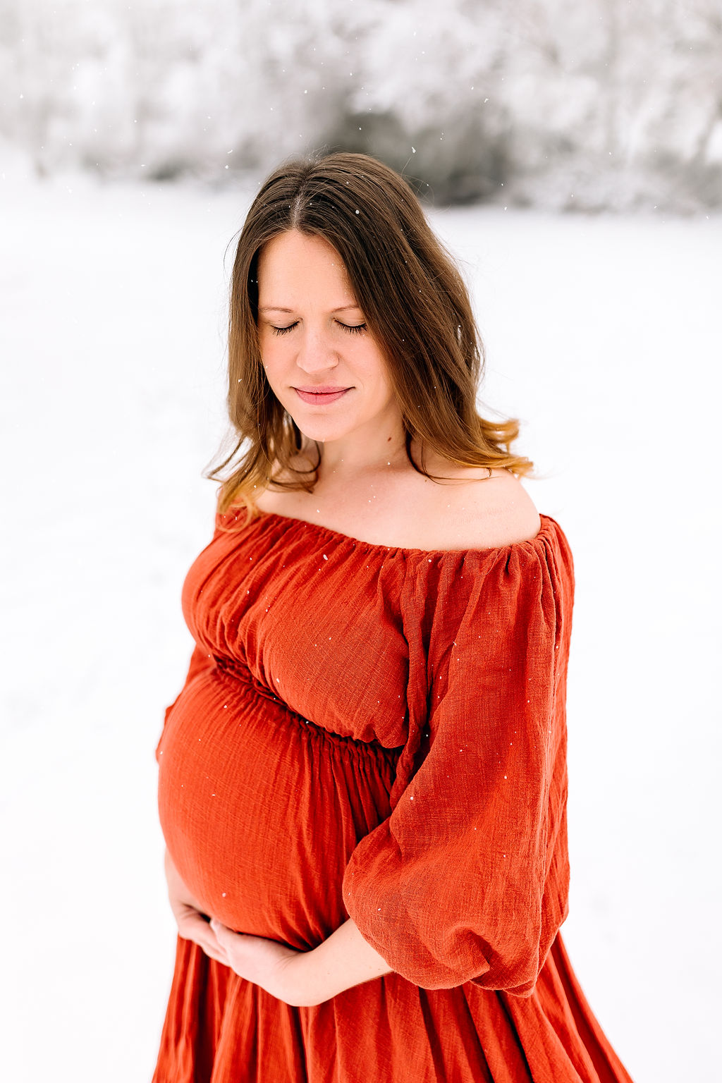 Motheer to be holds her bump as snow falls around her