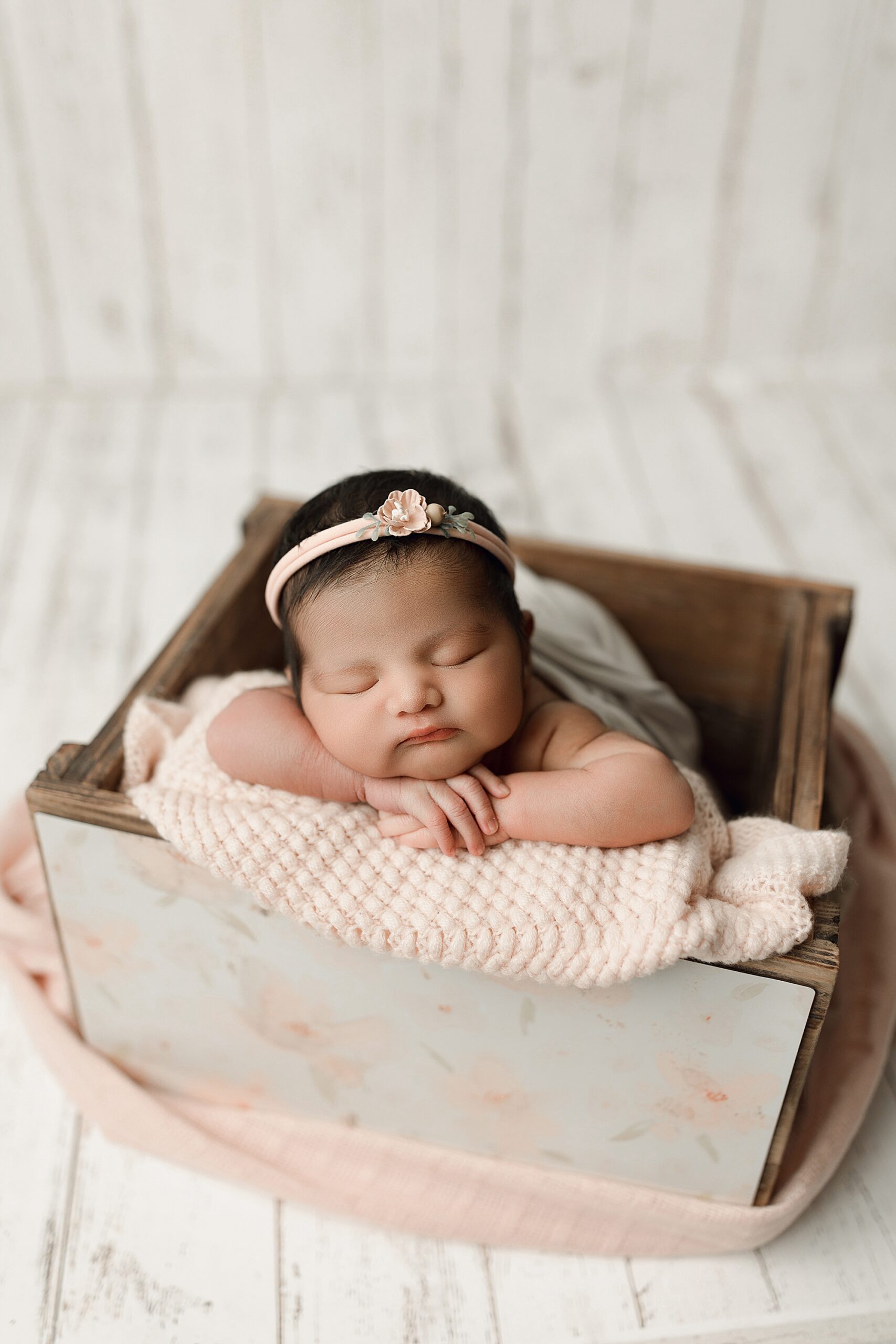 Newborn baby girl in a crate with flowers