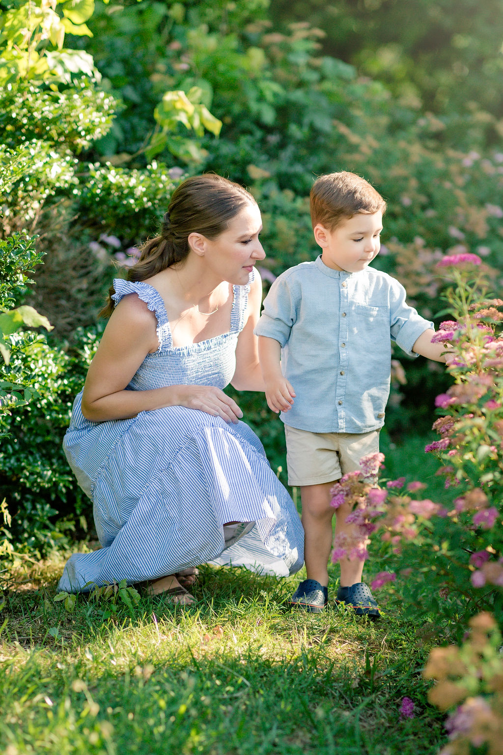 A mother and son explore a flower garden path with pink and white flowers