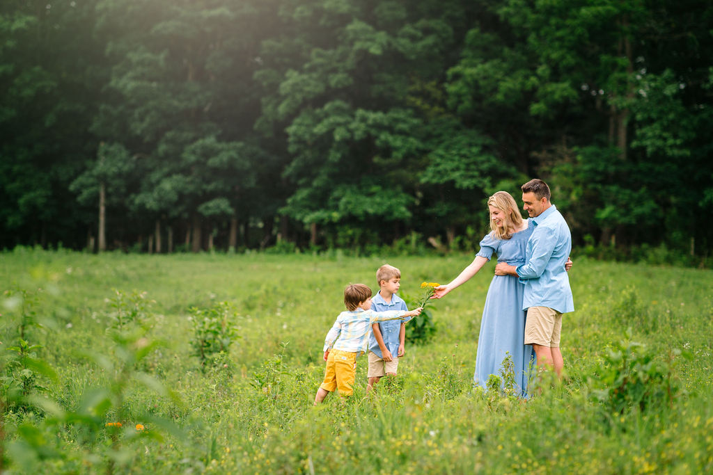 Mom and Dad are given wildflowers picked by their two sons in a grassy field