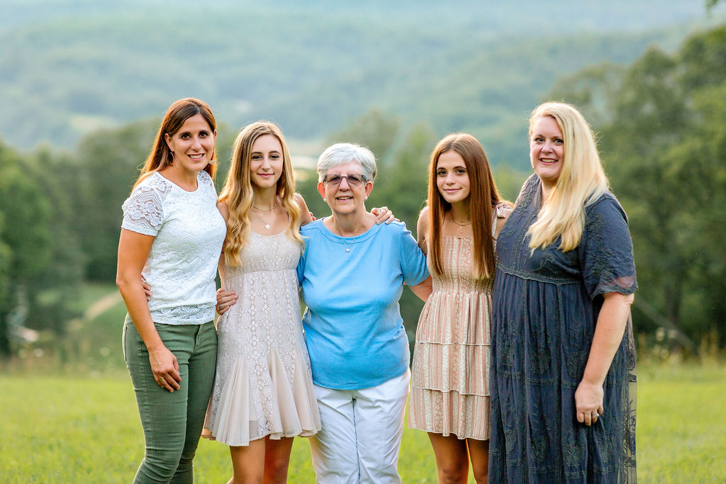 Five women spanning three generations stand on a hillside with arms around each other with grandma in the middle activities at massanutten resort