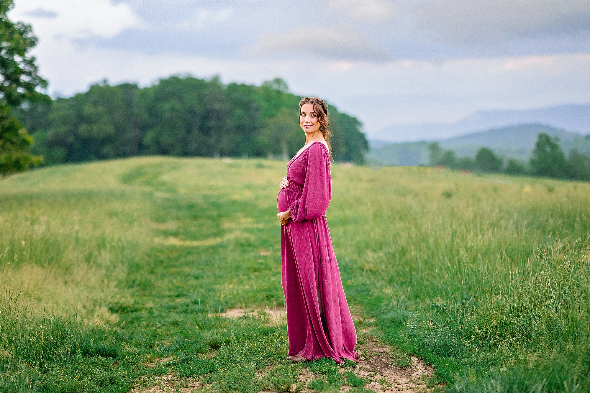 Maternity photos of mom wearing pink dress with mountain backdrop