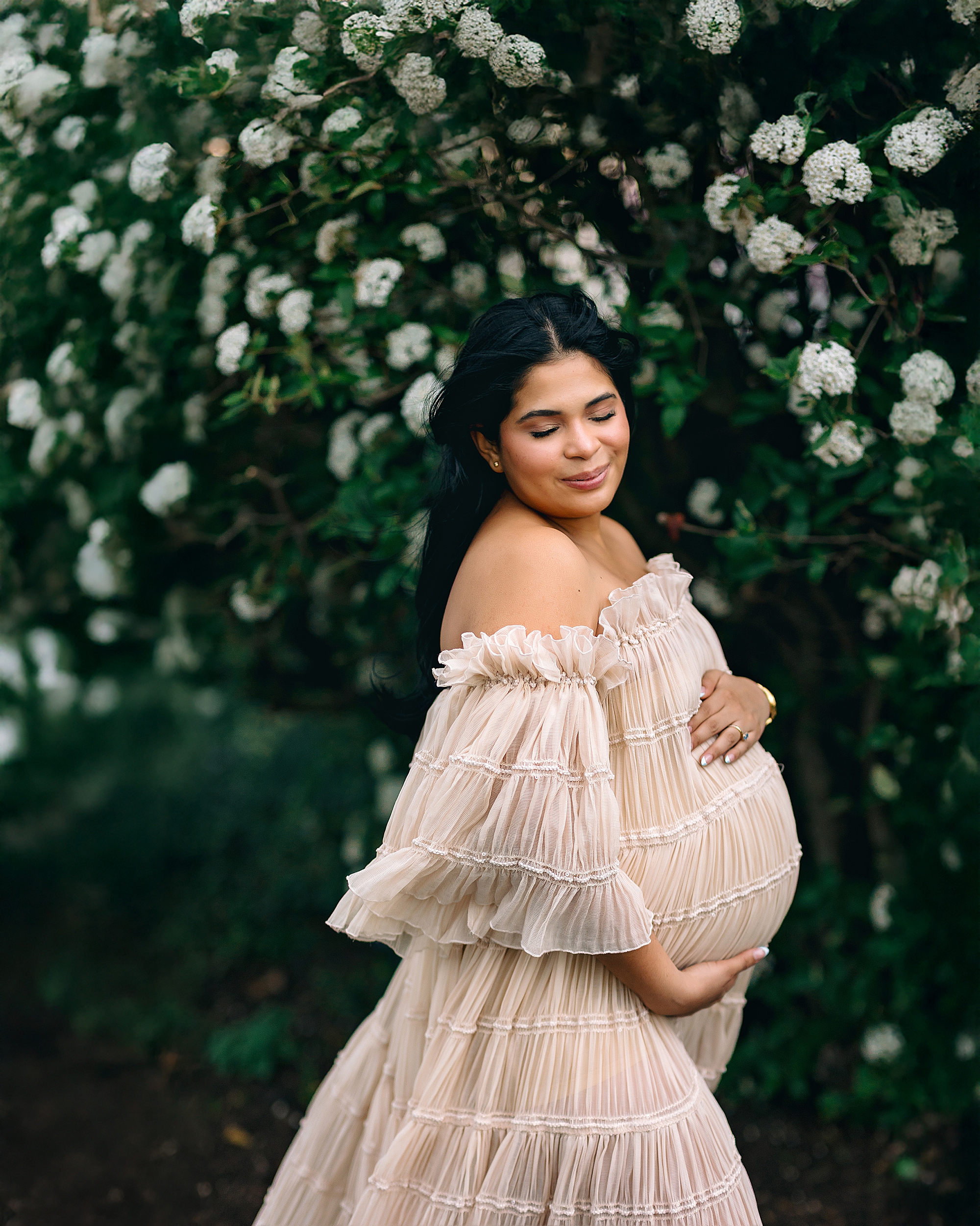 Pregnant mom posing in front of flowered bush