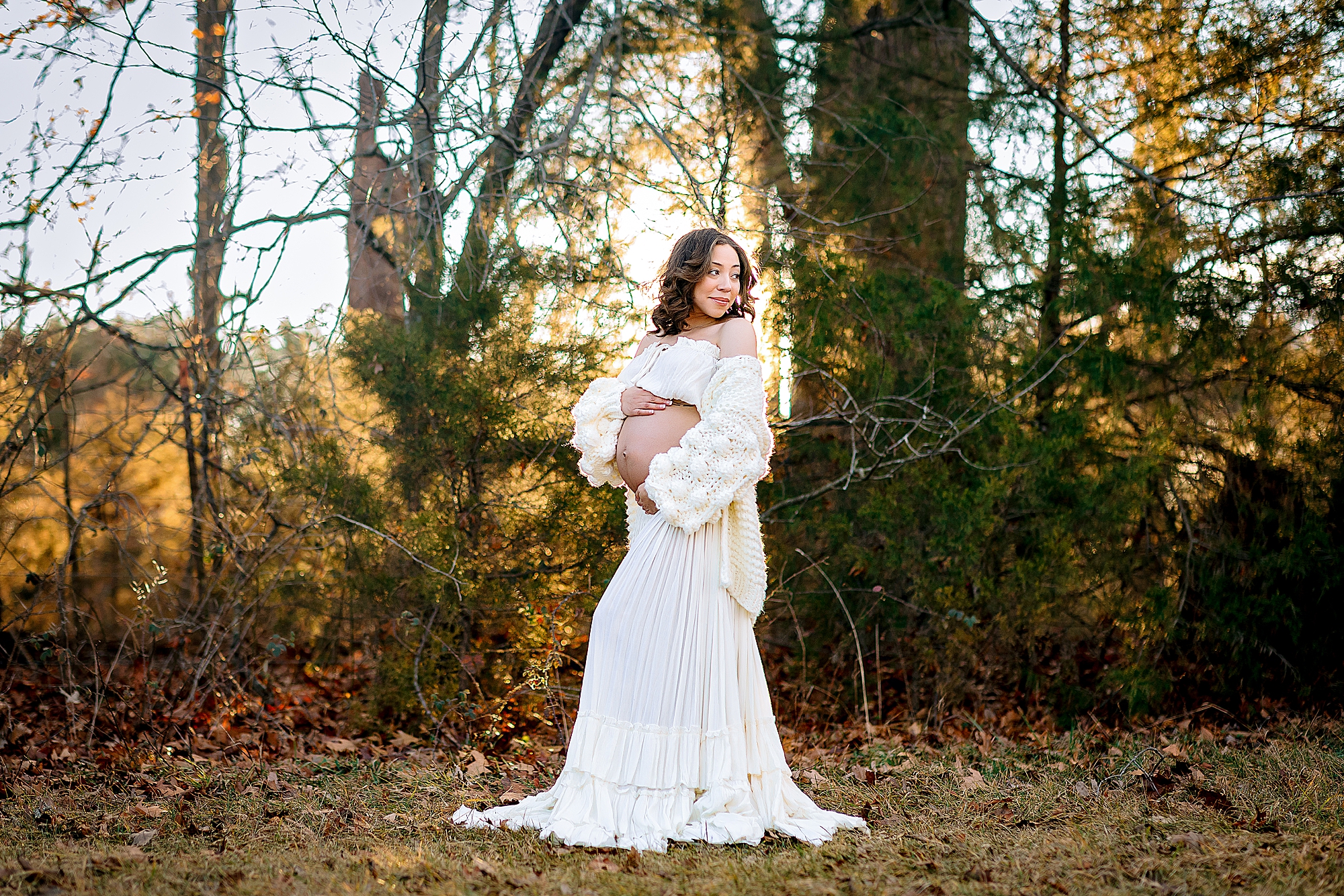 Pregnant woman in white dress in Harrisonburg VA with the sunset behind her