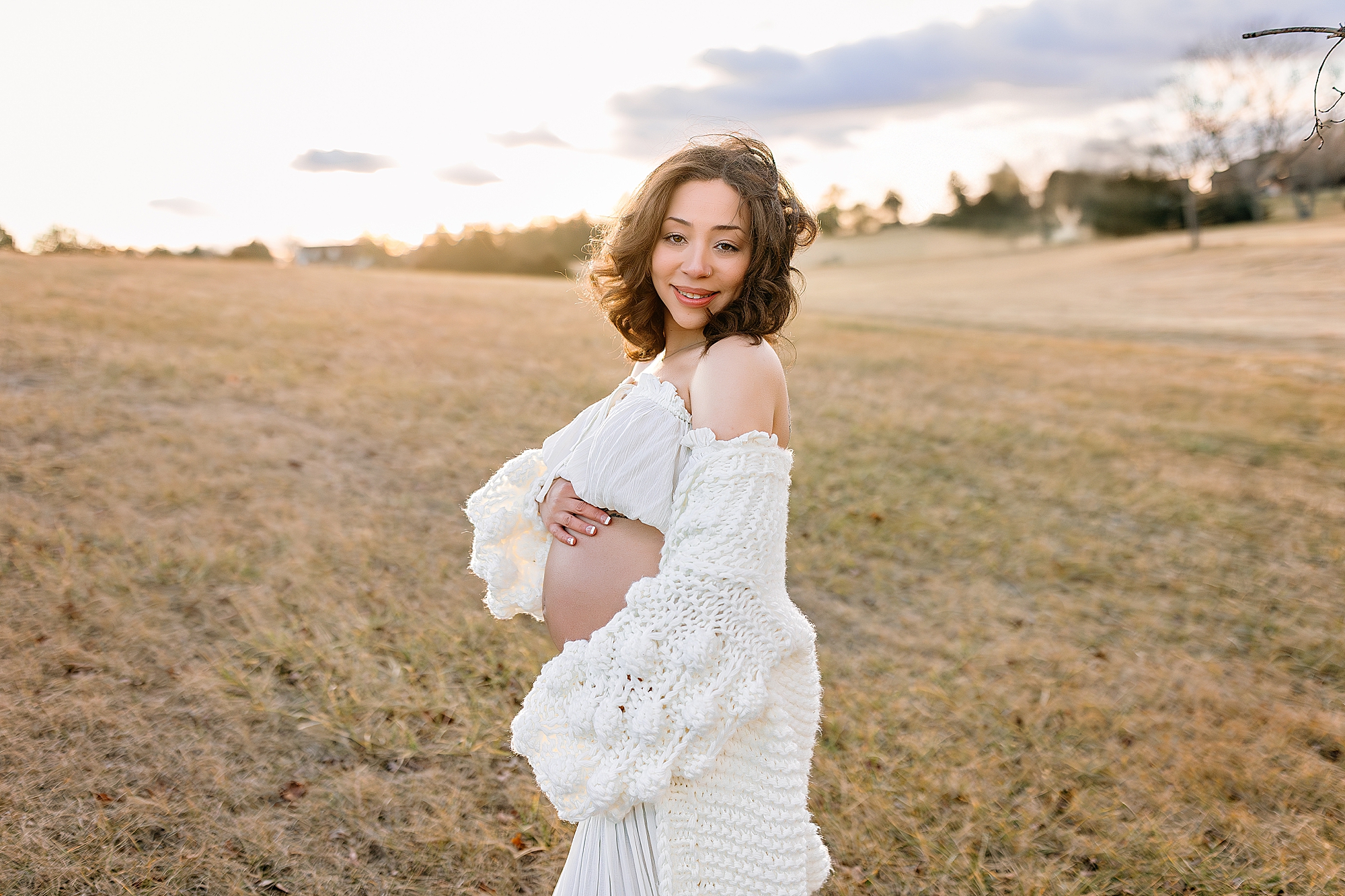 Pregnant mom in white dress in a field at sunset in Harrisonburg