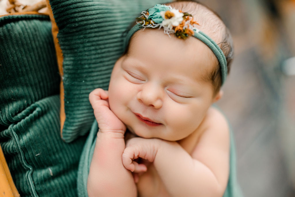 A newborn baby sleeps with a smile on green pillows uva pediatrics