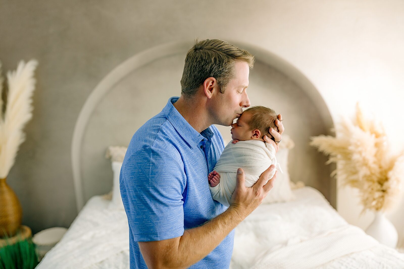 Dad kissing baby in newborn studio