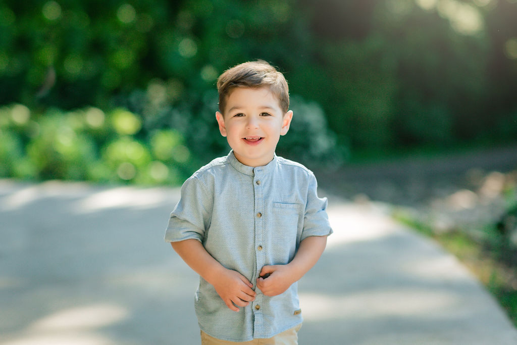 A young boy in a blue button-down shirt walks down a paved path in a park preschools in staunton va