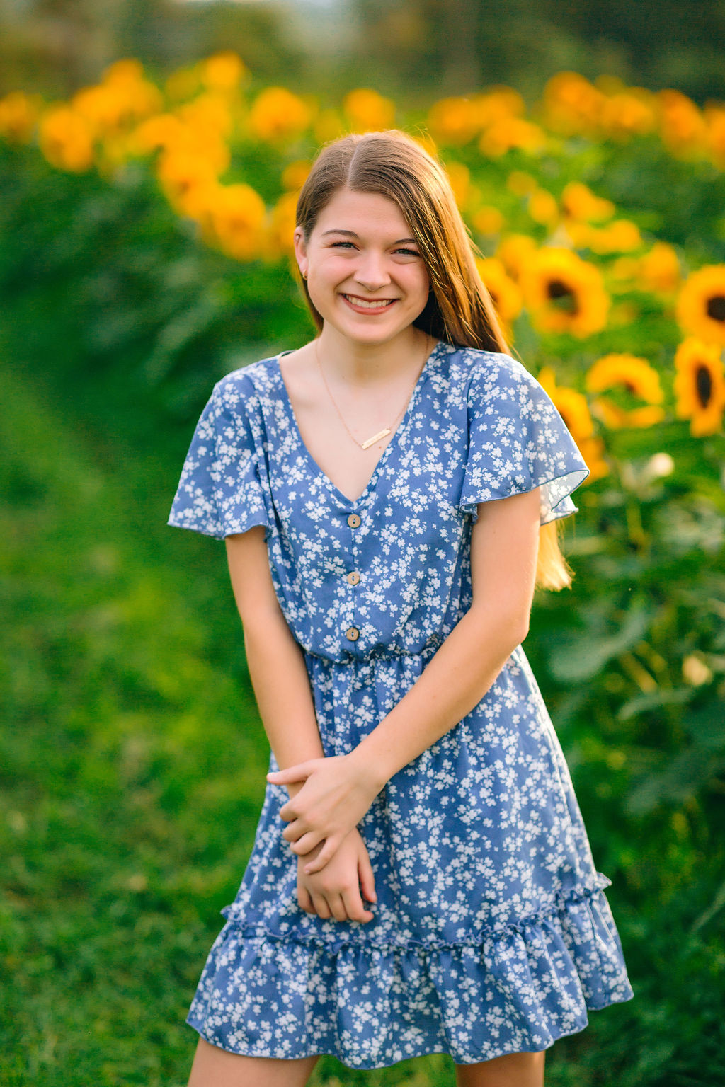 A young girl stands in a field of sunflowers wearing a blue and white dress rocktown dental