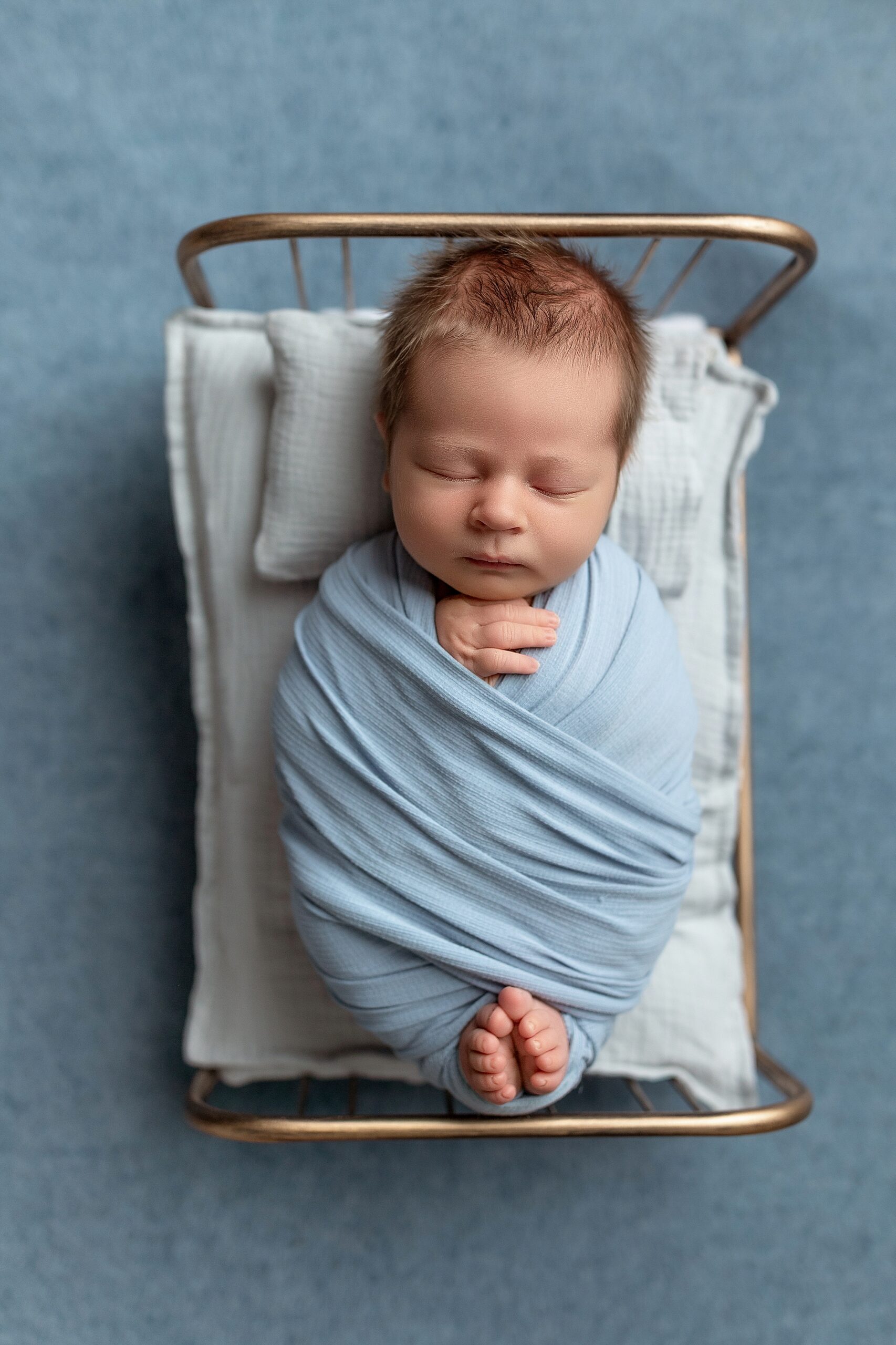 Newborn boy sleeps on tiny bed in blue Winchester VA daycare