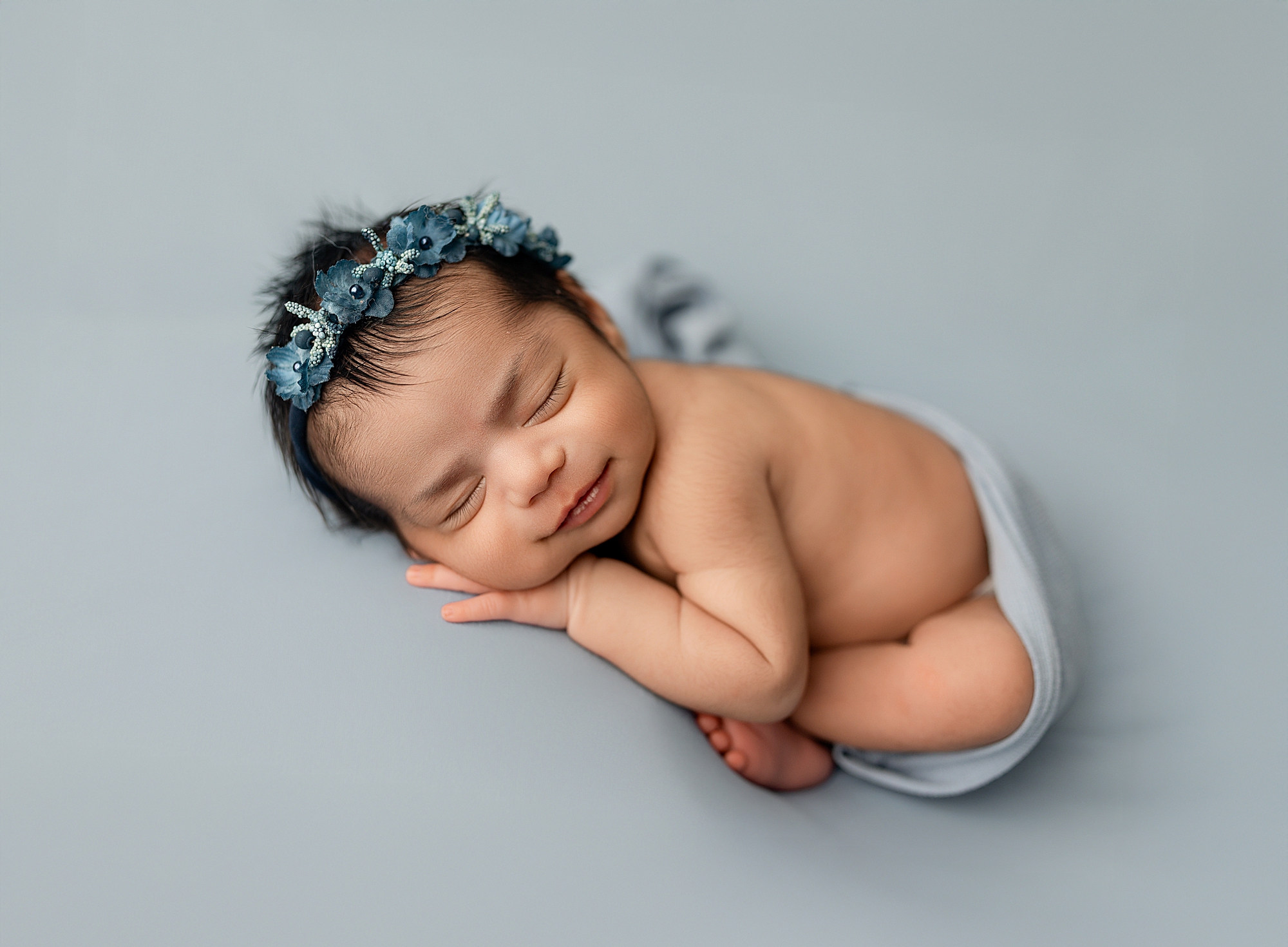 Baby girl on blue fabric with blue headband