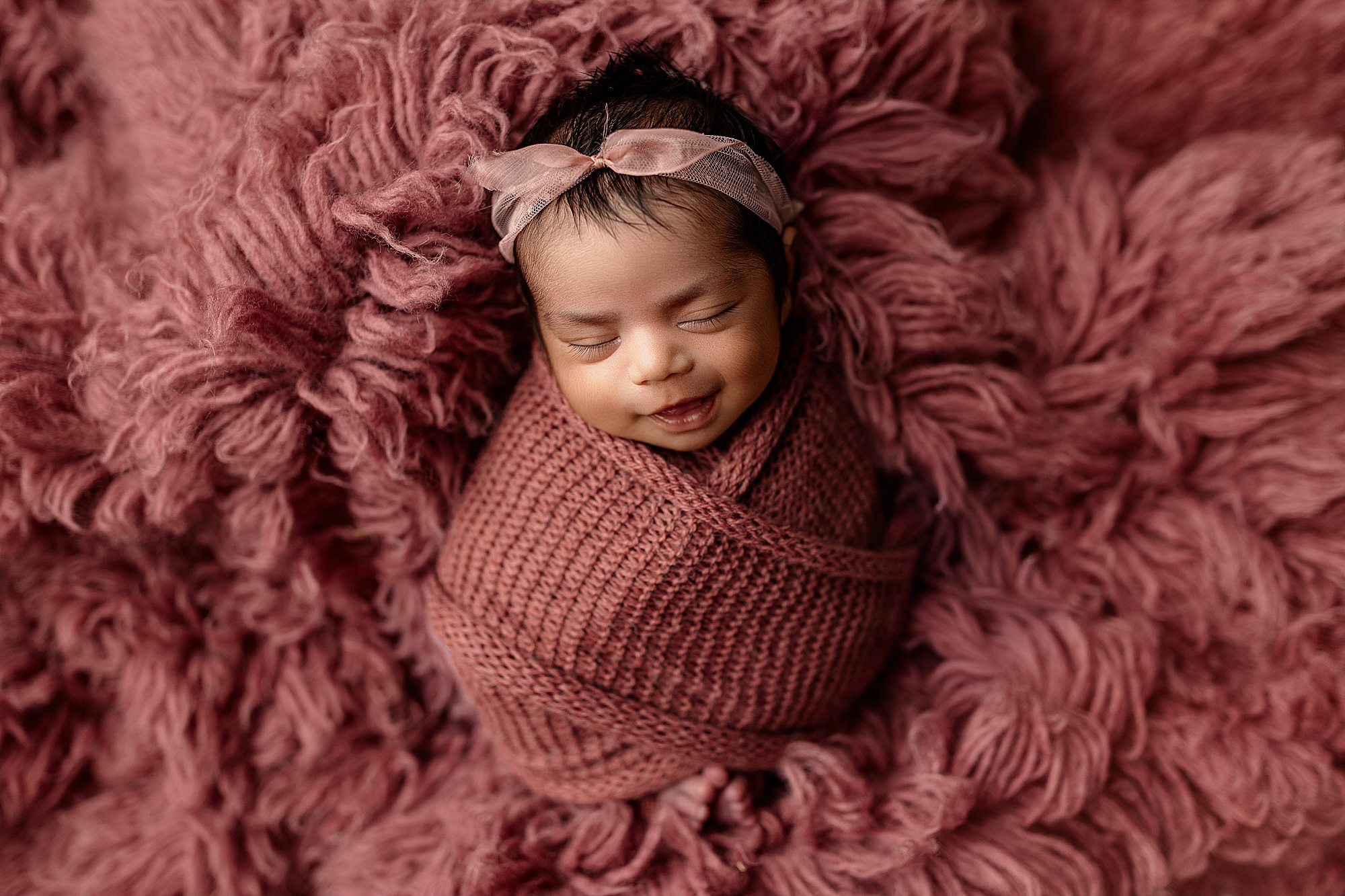 Newborn baby girl in pink smiling