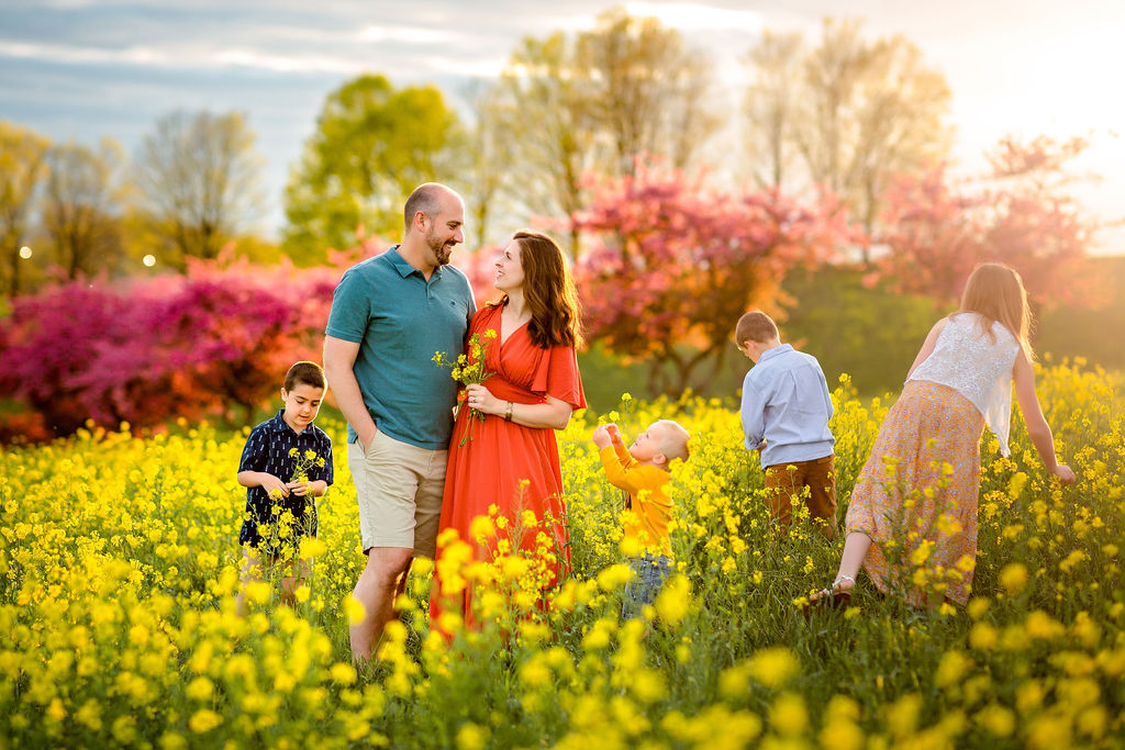 A mom and dad pick wildflowers with their four children