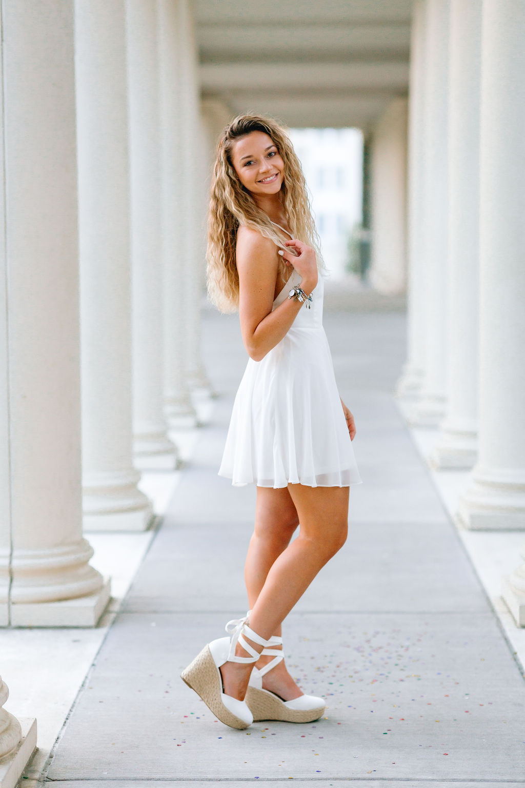 A college grad stands in a white dress playing with her hair thanks to jmu tutoring