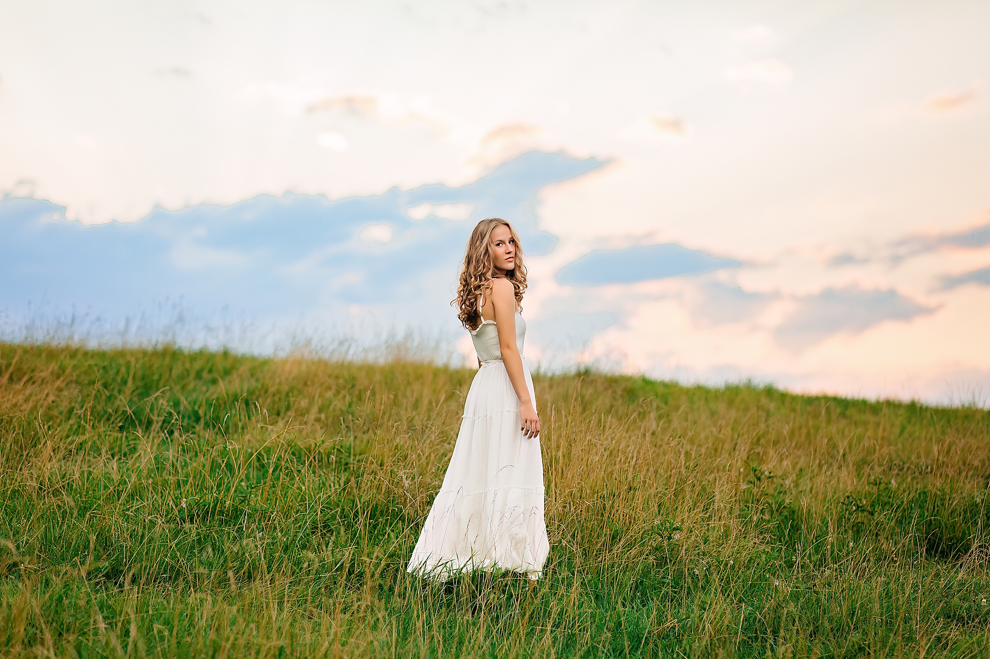 Harrisonburg Senior girl in a long white dress walking through a field in Rockingham County